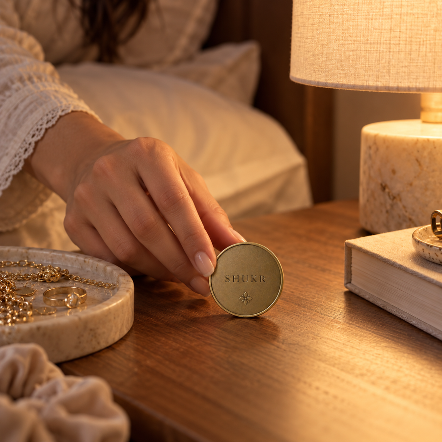 AI-generated editorial lifestyle image showing the Shukr Coin kept beside a bedside journal. community moment